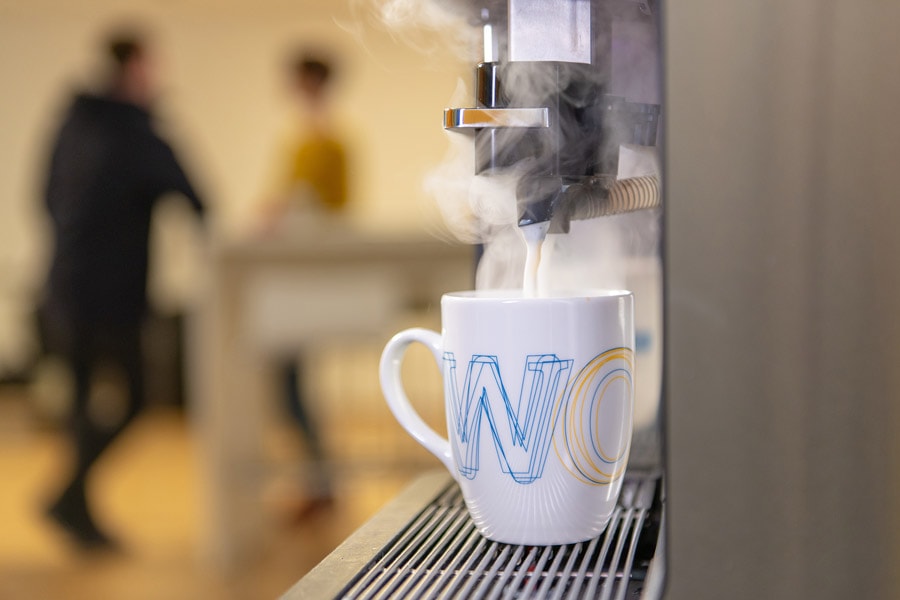 Aus einem Kaffeeautomaten läuft Kaffee in eine Tasse