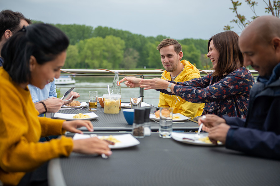 Mitarbeiter grillen und essen in der Mittagspause gemeinsam